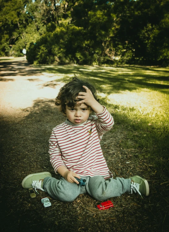 a small child sitting on the ground with a cell phone