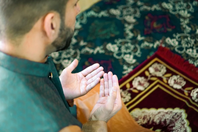 a man praying in front of an oriental rug