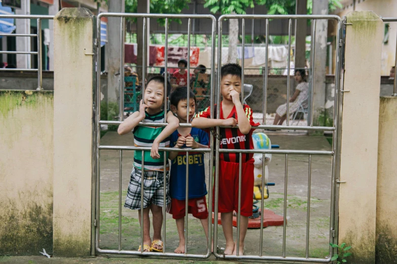 two boys stand behind bars on the street