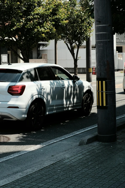 the side view of a white car parked at the edge of the street