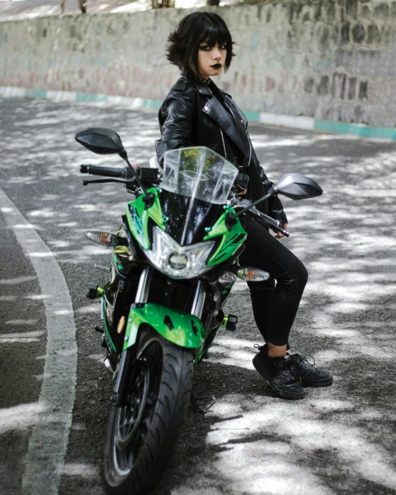 woman in leather clothing sitting on a green motorcycle