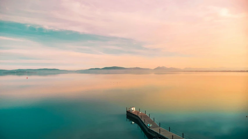 a wooden pier is near the water and some mountains