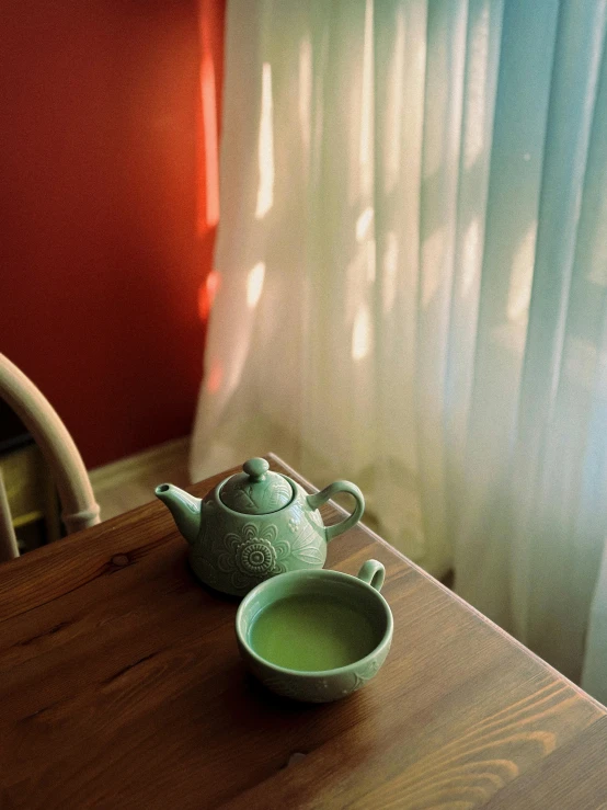 a teapot sits on the dining table beside a white bowl