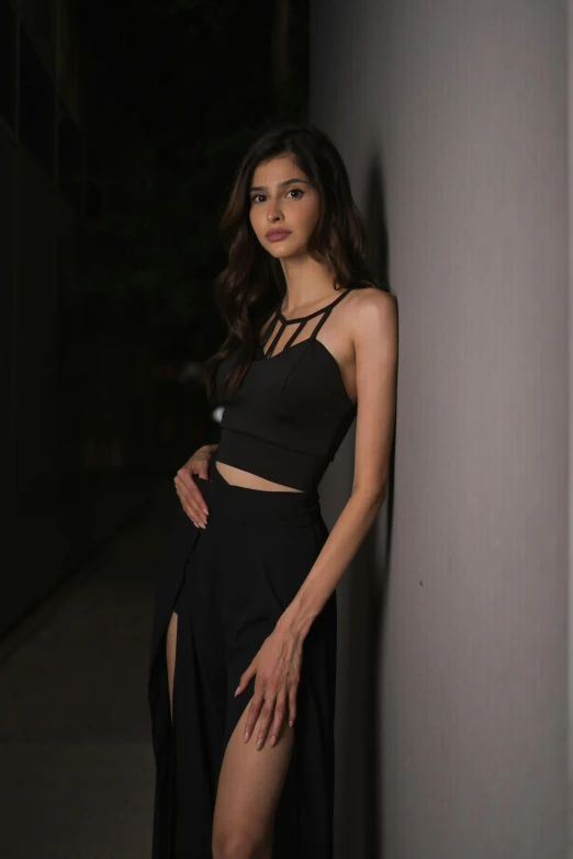 a woman wearing a slit top and a black skirt posing in a dark alley