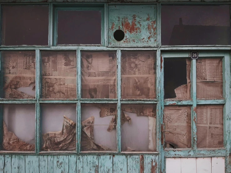 broken and worn old window with newspaper papers in the window