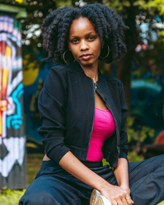 a woman in a black jacket is sitting on the grass