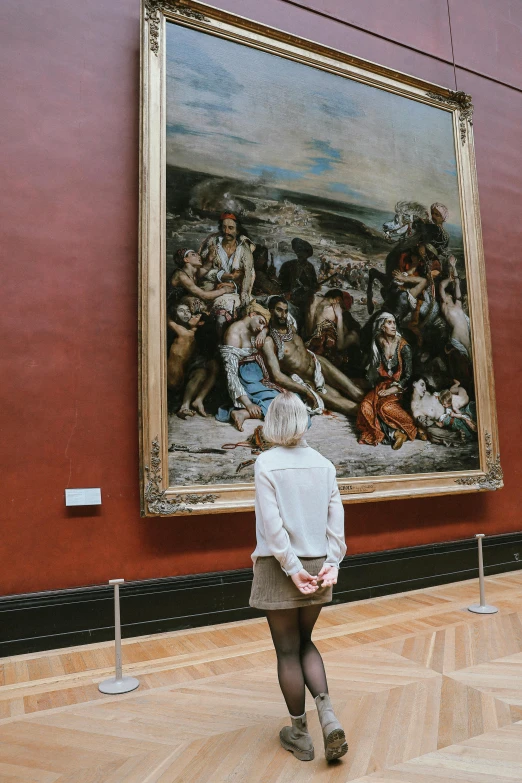 a woman looks at a painting hanging in the hall