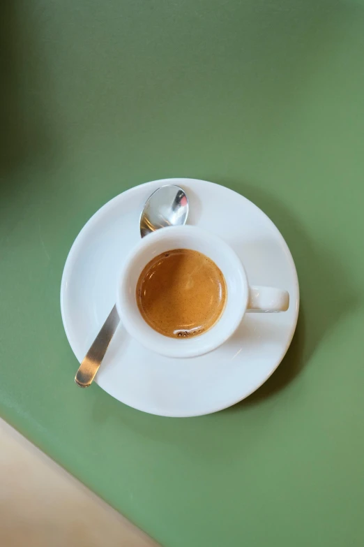 an espresso in white cup on a saucer and spoon with spoon