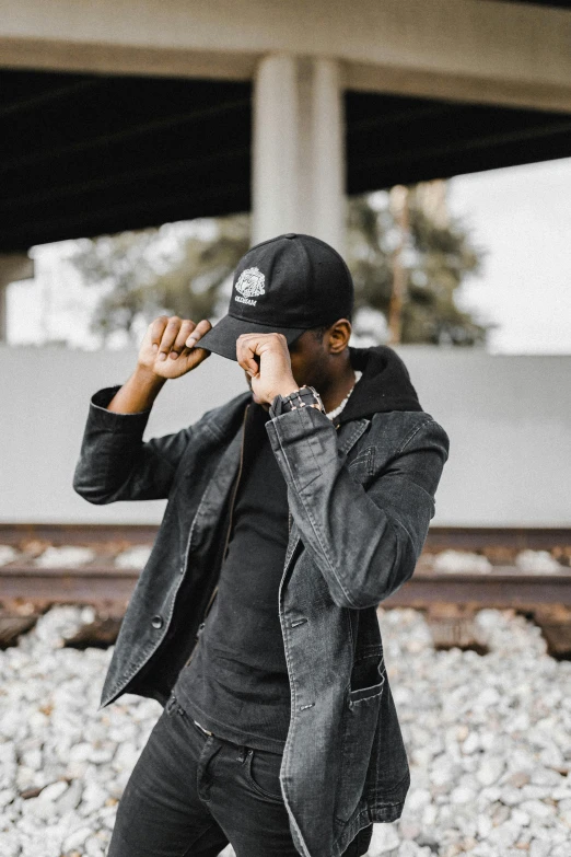 a man in black clothes is standing near railroad tracks