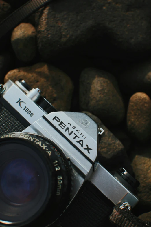 a camera sitting on a rocky beach by some rocks