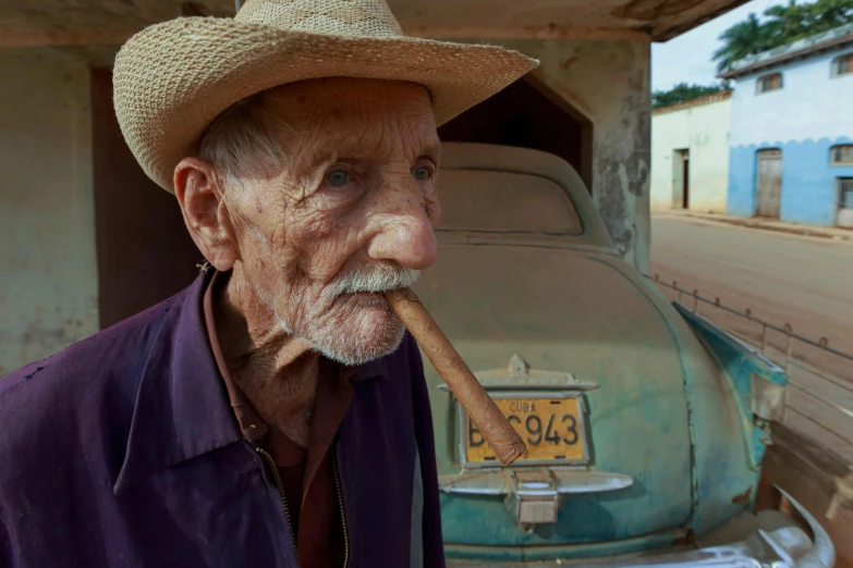 an old man with a straw hat chewing on a pipe