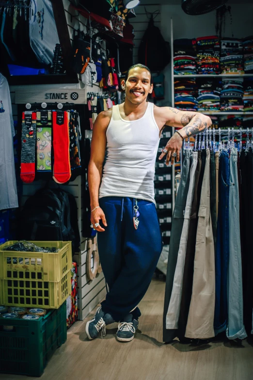 man with arms out, surrounded by various shirts and merchandise