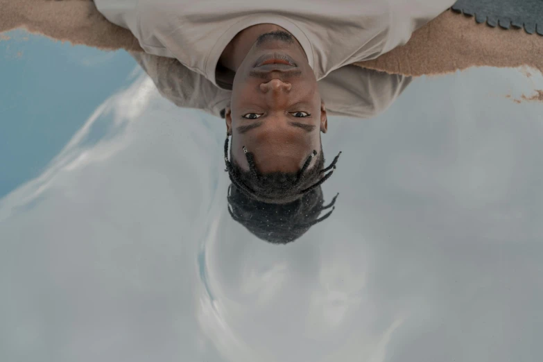 a man wearing white clothing and a goatee is swimming in a body of water