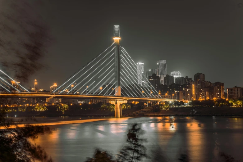 a city skyline from across the river with lit up bridge