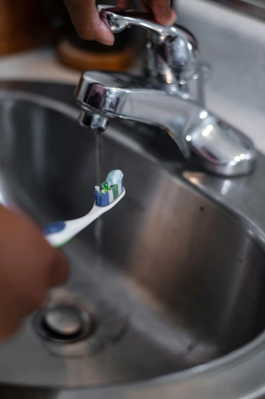 someone is brushing their teeth in the sink