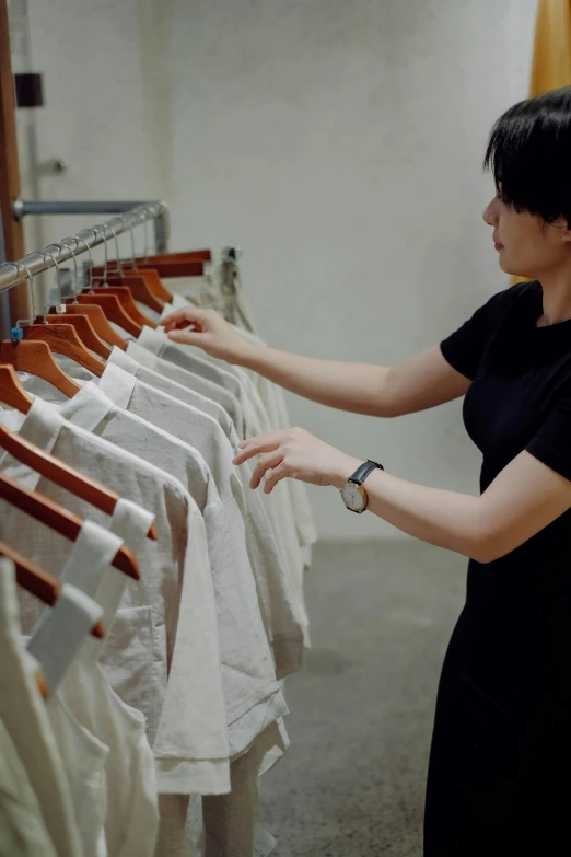 a woman looking at a rack of women's clothing on a rail