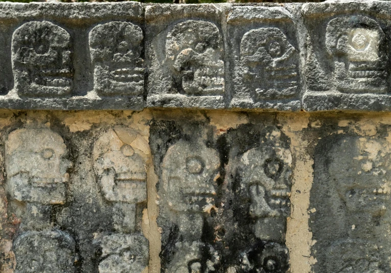 stone carvings with faces are on a wall