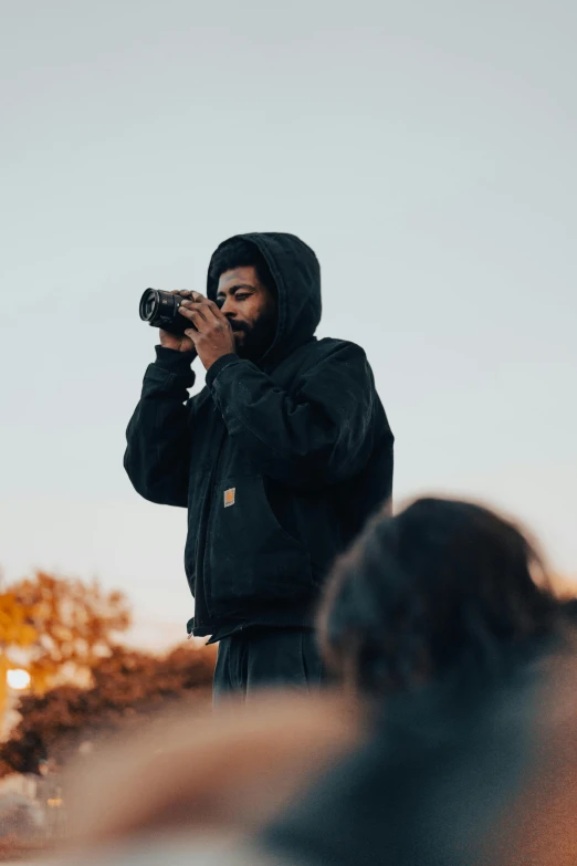 a man in a hoodie taking pictures with his camera