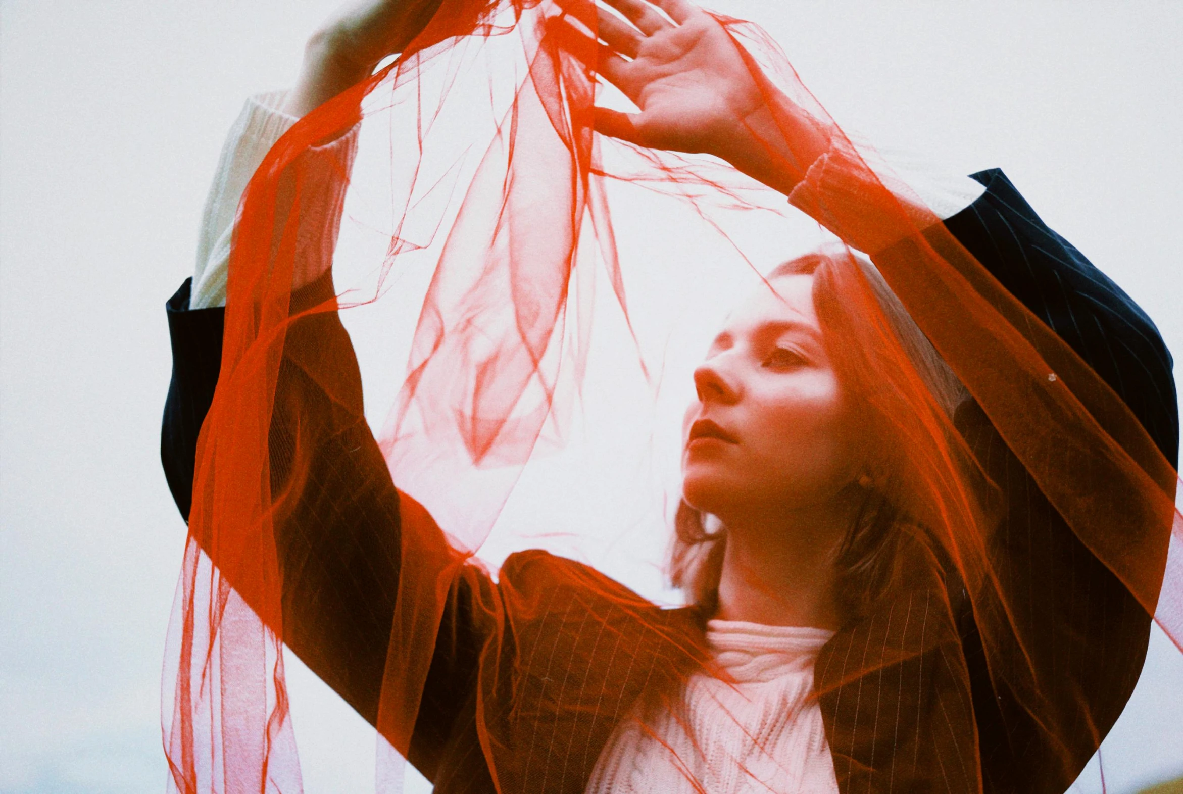 a woman posing underneath a red scarf