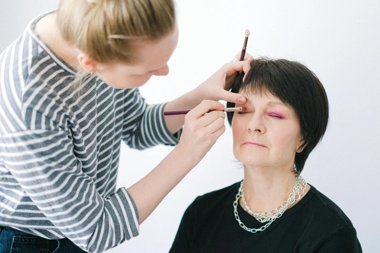 woman getting makeup applied with brush near mirror