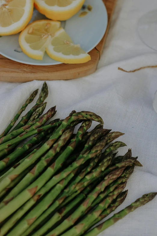 a plate full of asparagus with lemons in the background