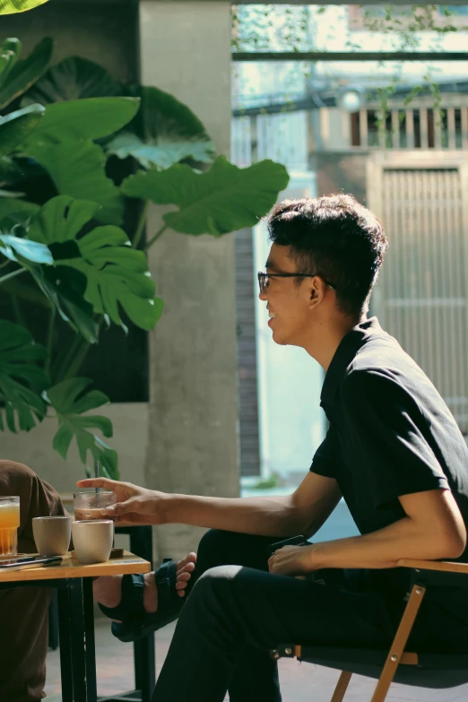 two men sitting at a table together drinking coffee