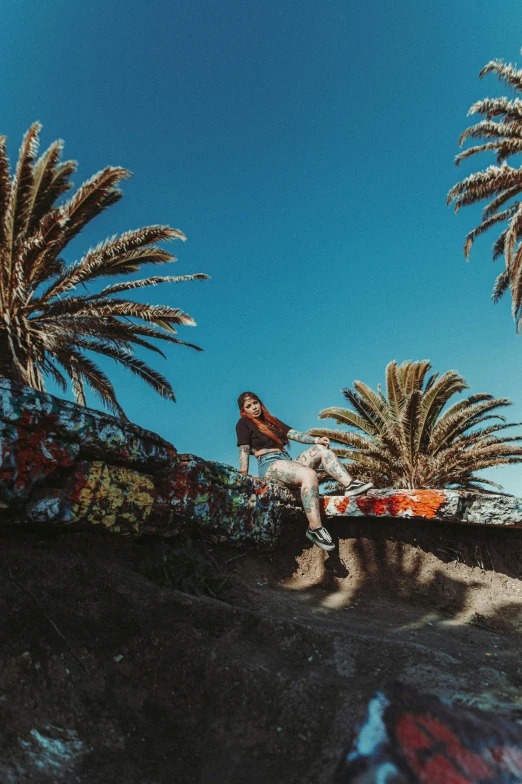 a woman is sitting under palm trees in the sun