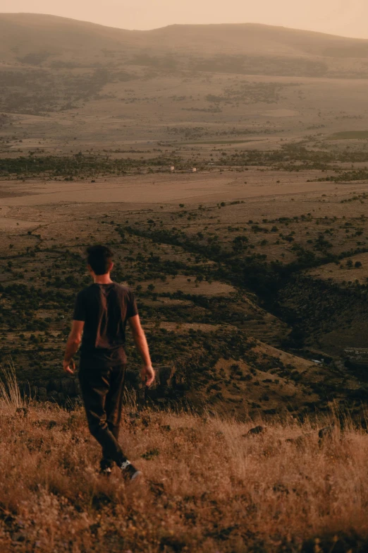 young man walking across a grass covered valley