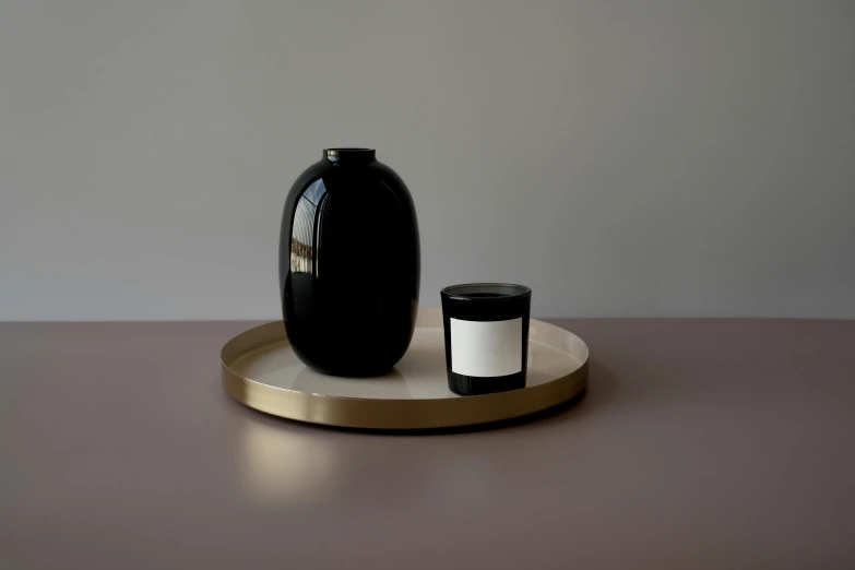 a vase sits on a tray next to a candle