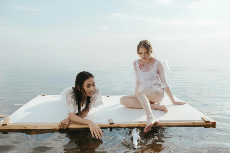 two s sitting on some boards in the water