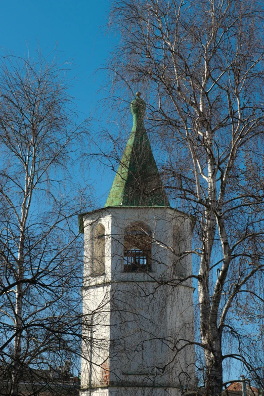 a tower with a green roof surrounded by many trees