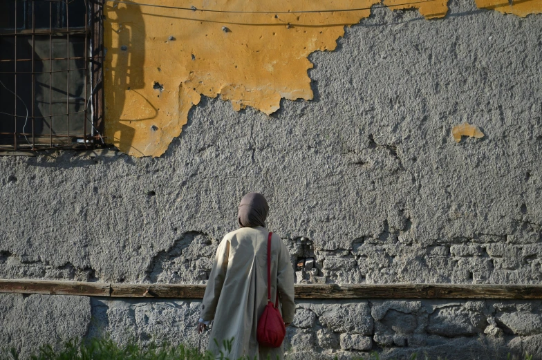a woman wearing a long coat walking past a building