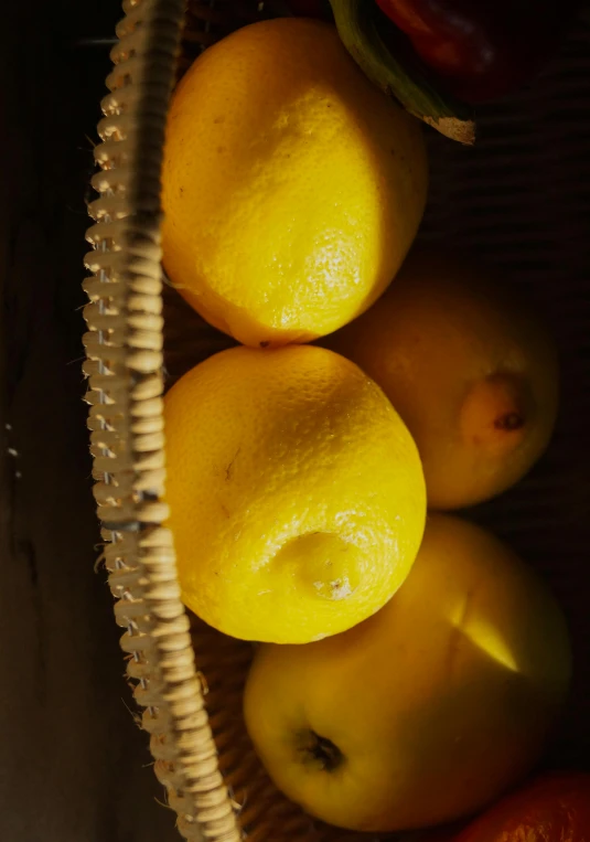 a group of lemons and apples in a basket