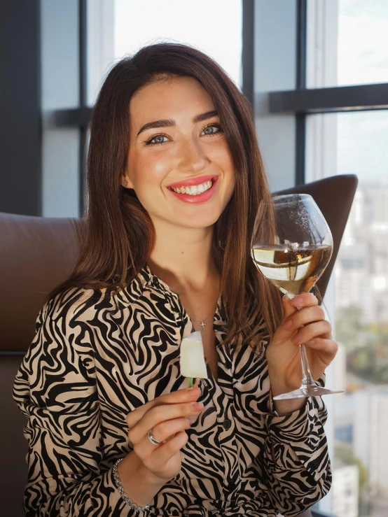 a woman holding a glass and wine in front of a window