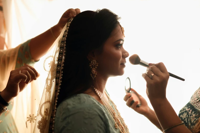 a bride gets makeup done in preparation for her wedding