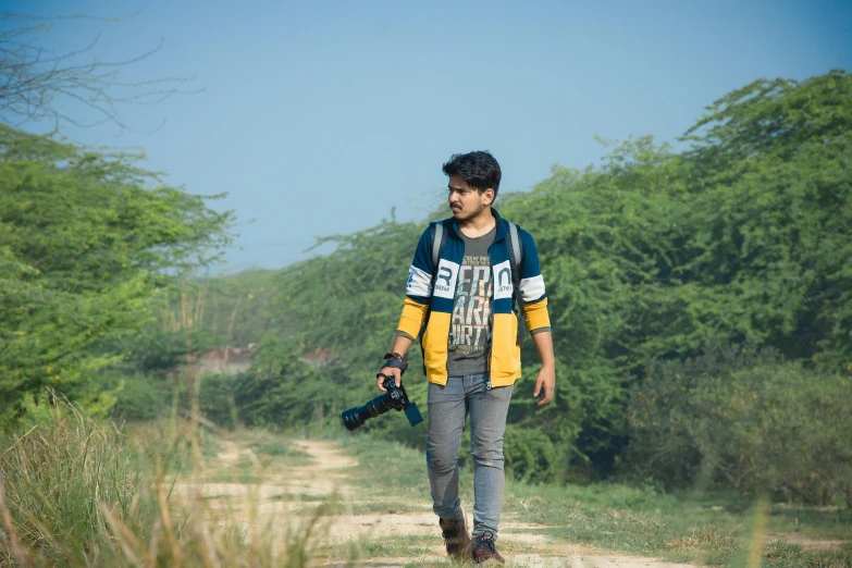 a person wearing a yellow jacket and black shoes walks down a dirt road