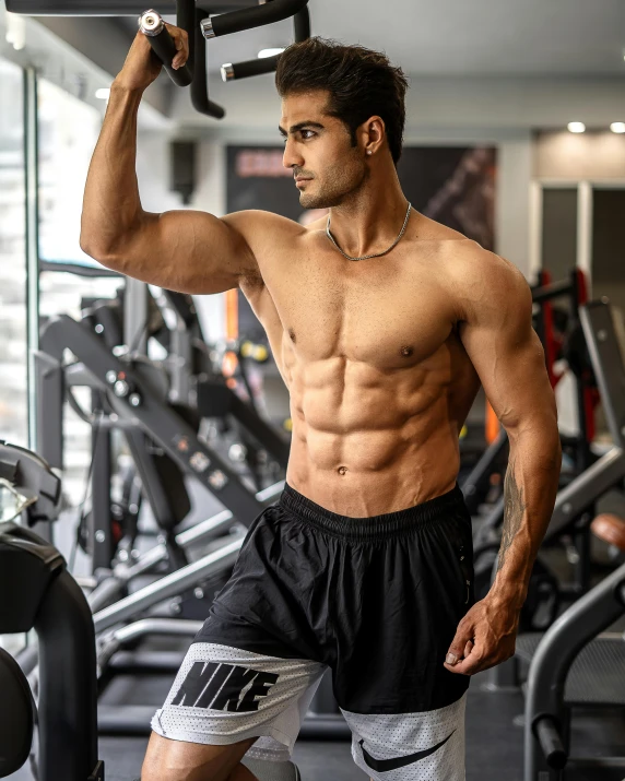 a shirtless man lifts up a gym bar