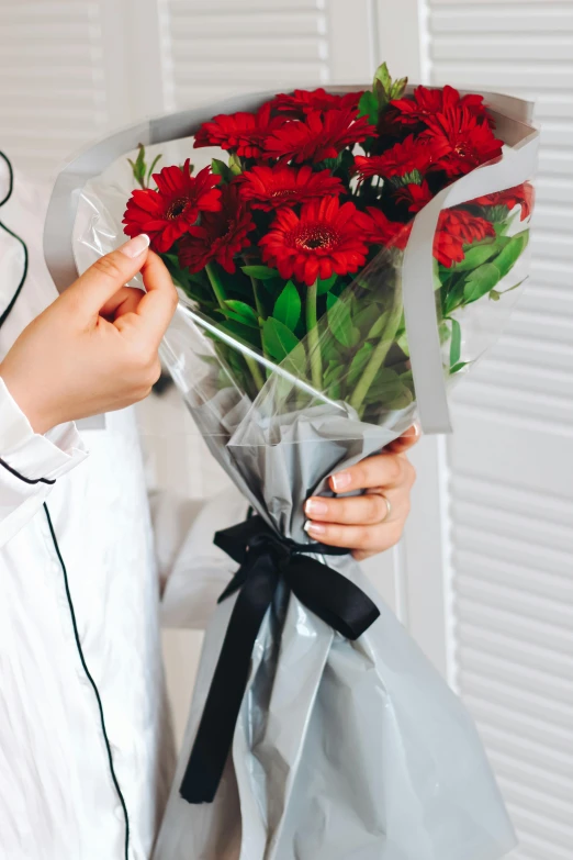 a person holding a bouquet of flowers and a paper wrapped in clear wrapping