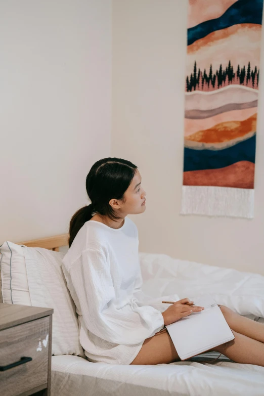 woman sitting on bed wearing white clothing