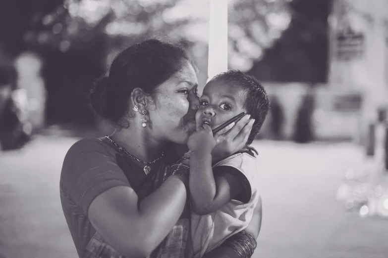 a woman holding a child who is standing near a pole