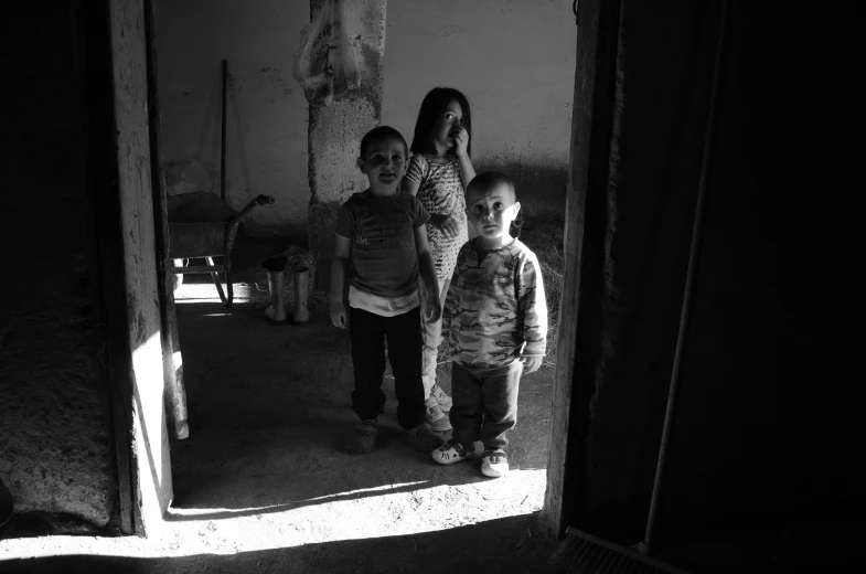 three little children standing next to each other outside a door