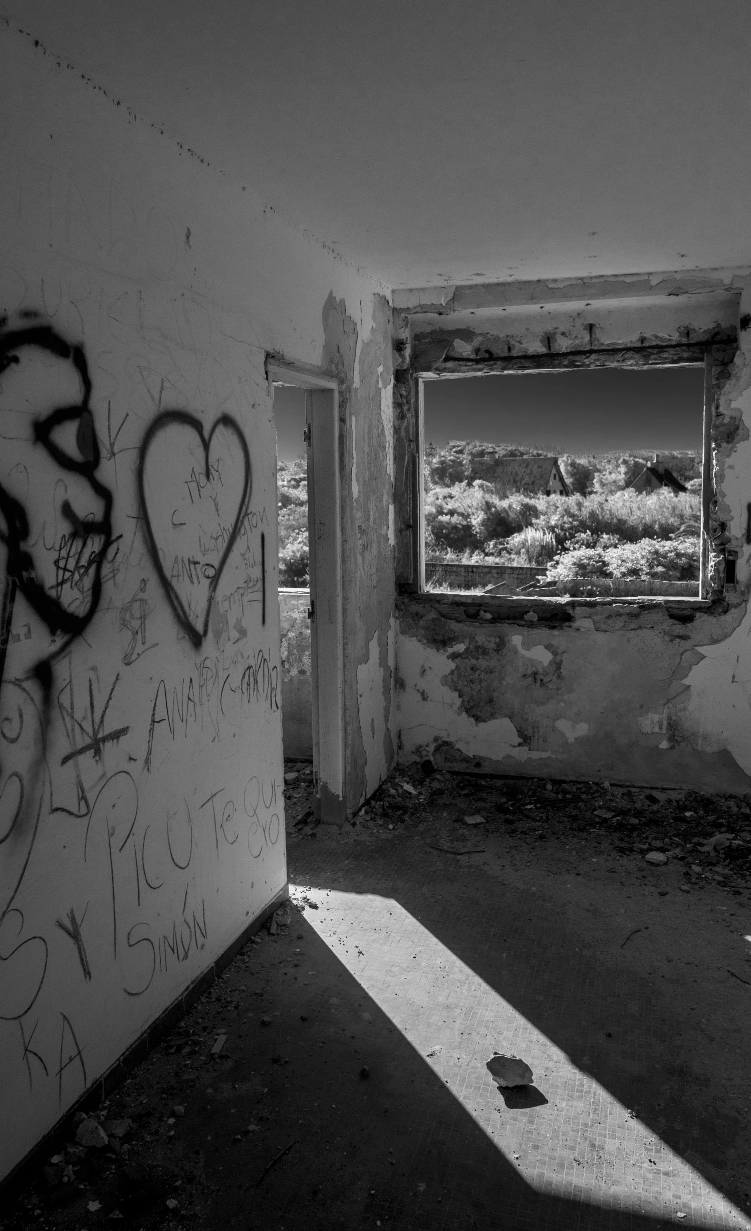 a dark, abandoned and open door leads into an area with graffiti