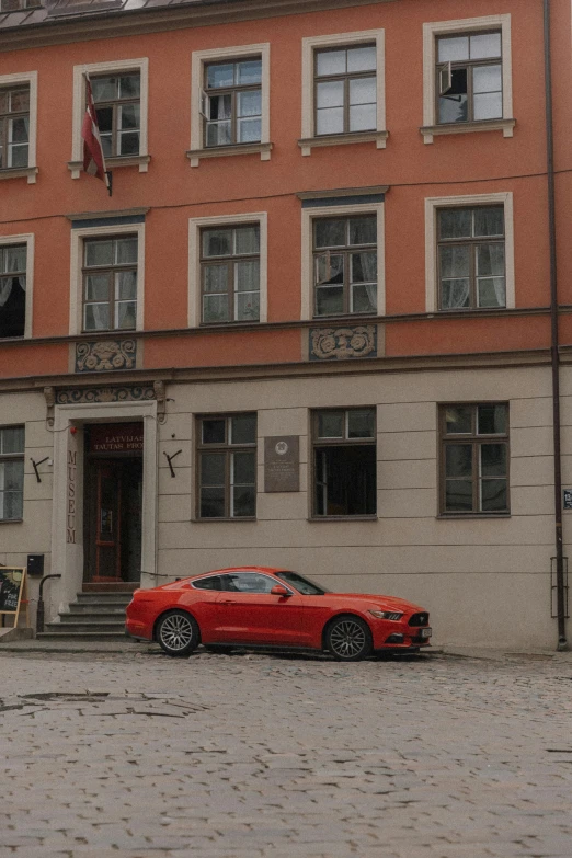 a red convertible car parked next to a tall red building