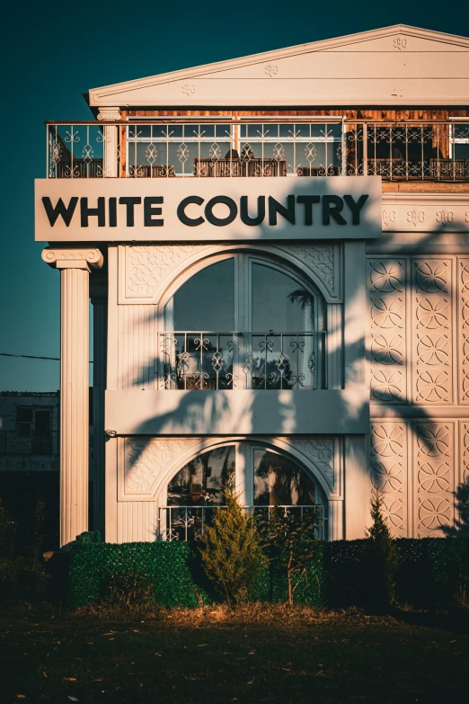 a white country building with palm trees shadow