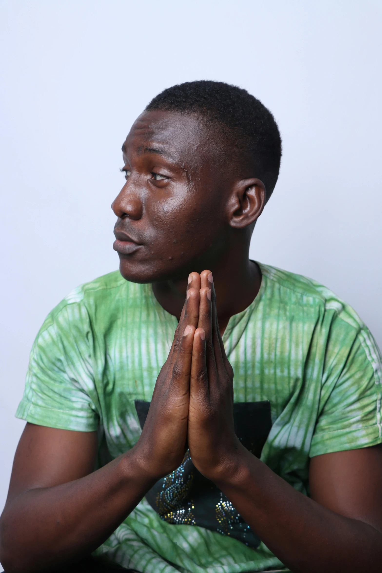 a young man wearing a green shirt doing some kind of praying