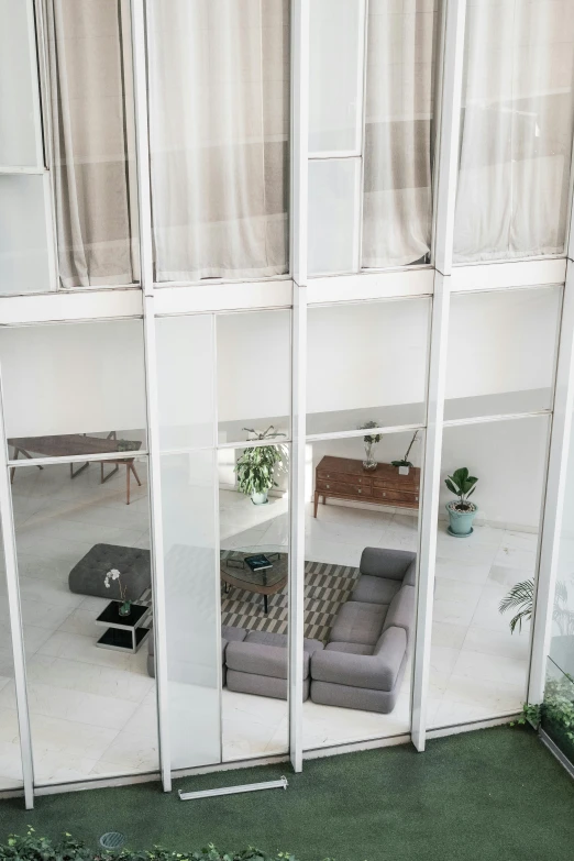 a large window in the front of an apartment building with white walls and green grass outside