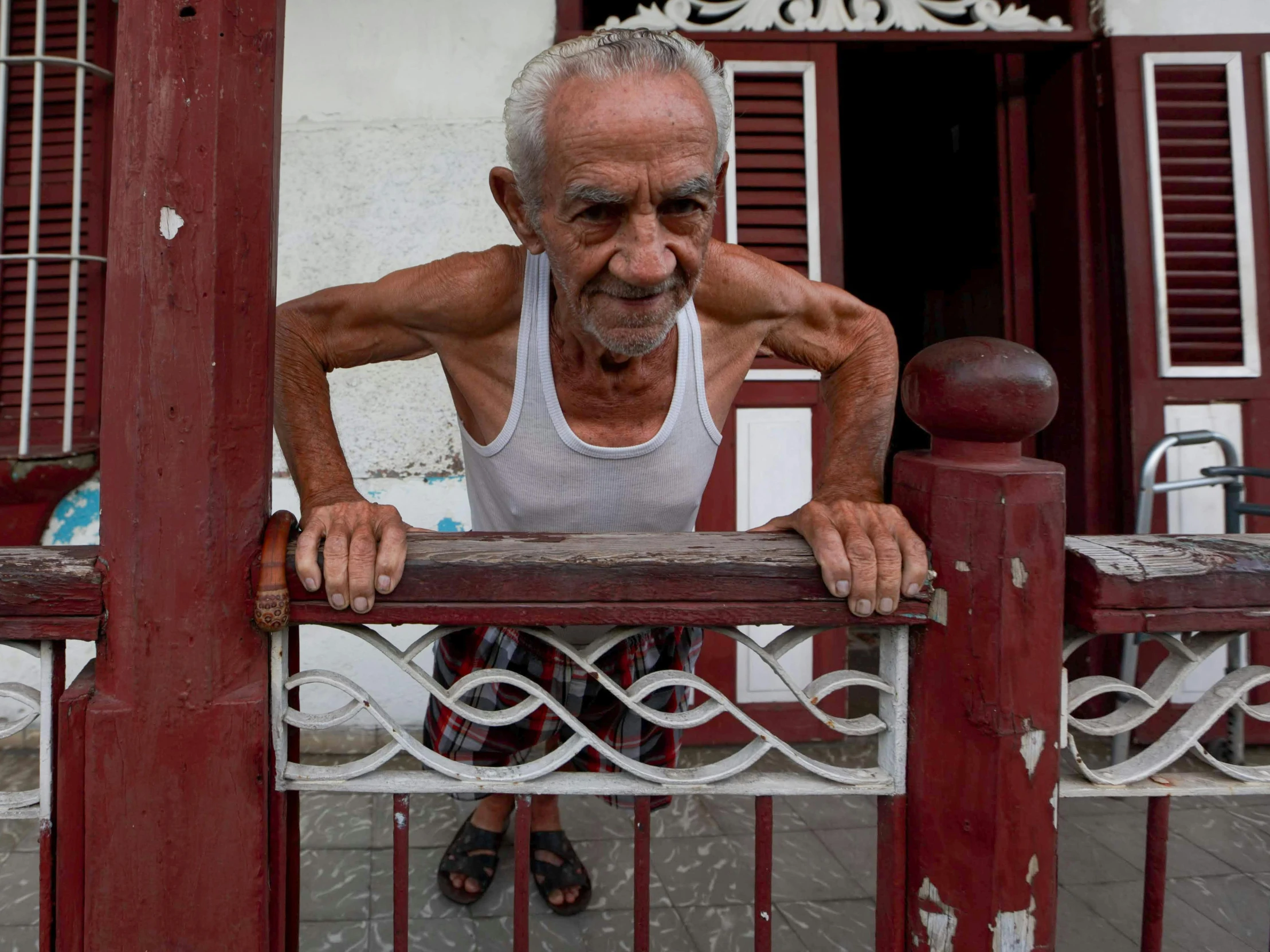 a man leaning on a red fence in front of a building