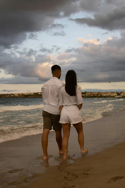 a couple standing next to each other on a beach