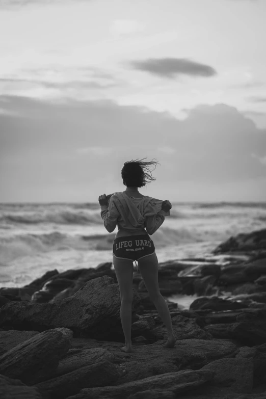 a person on rocks looking at the ocean