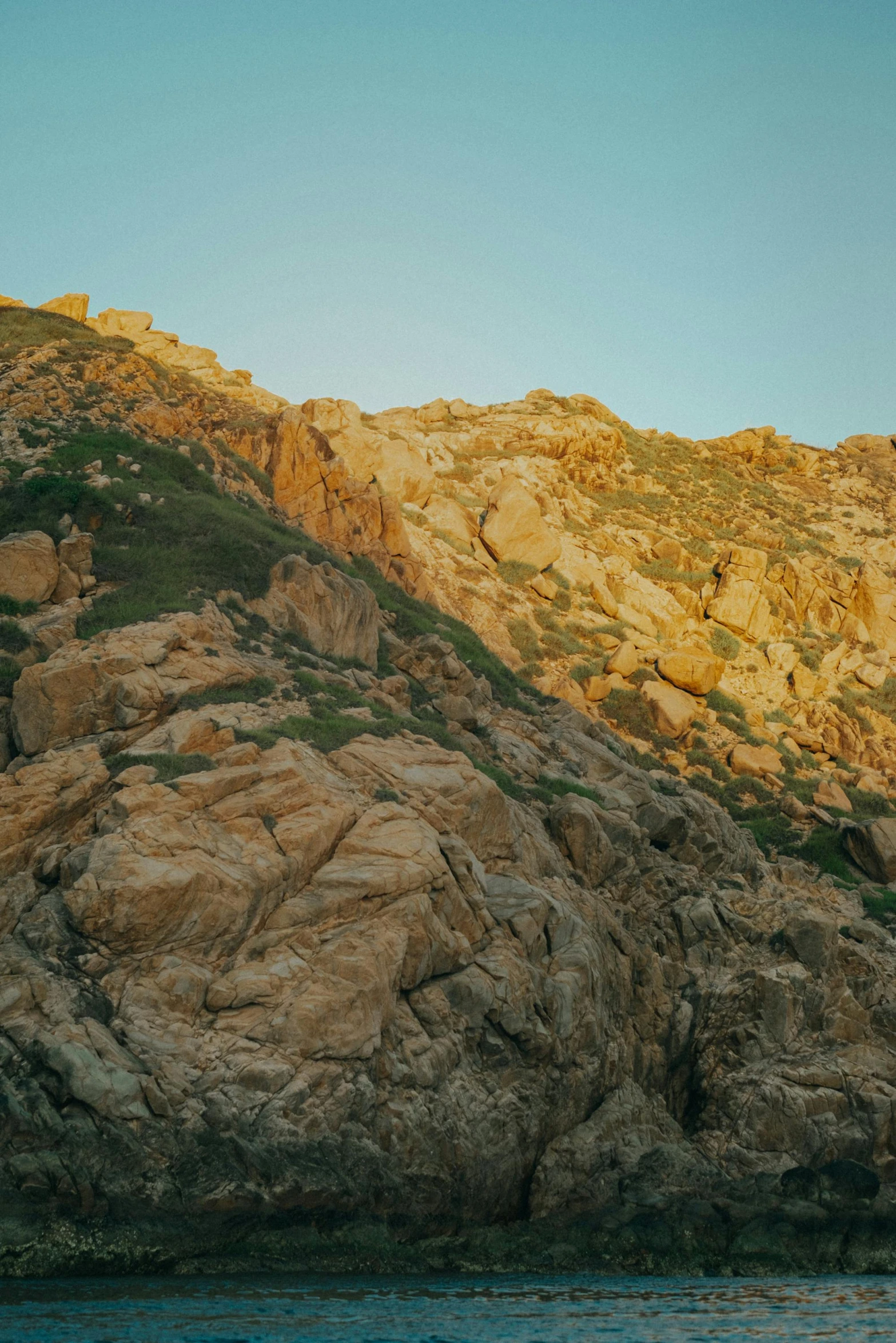 the side of a mountain in front of water and rock